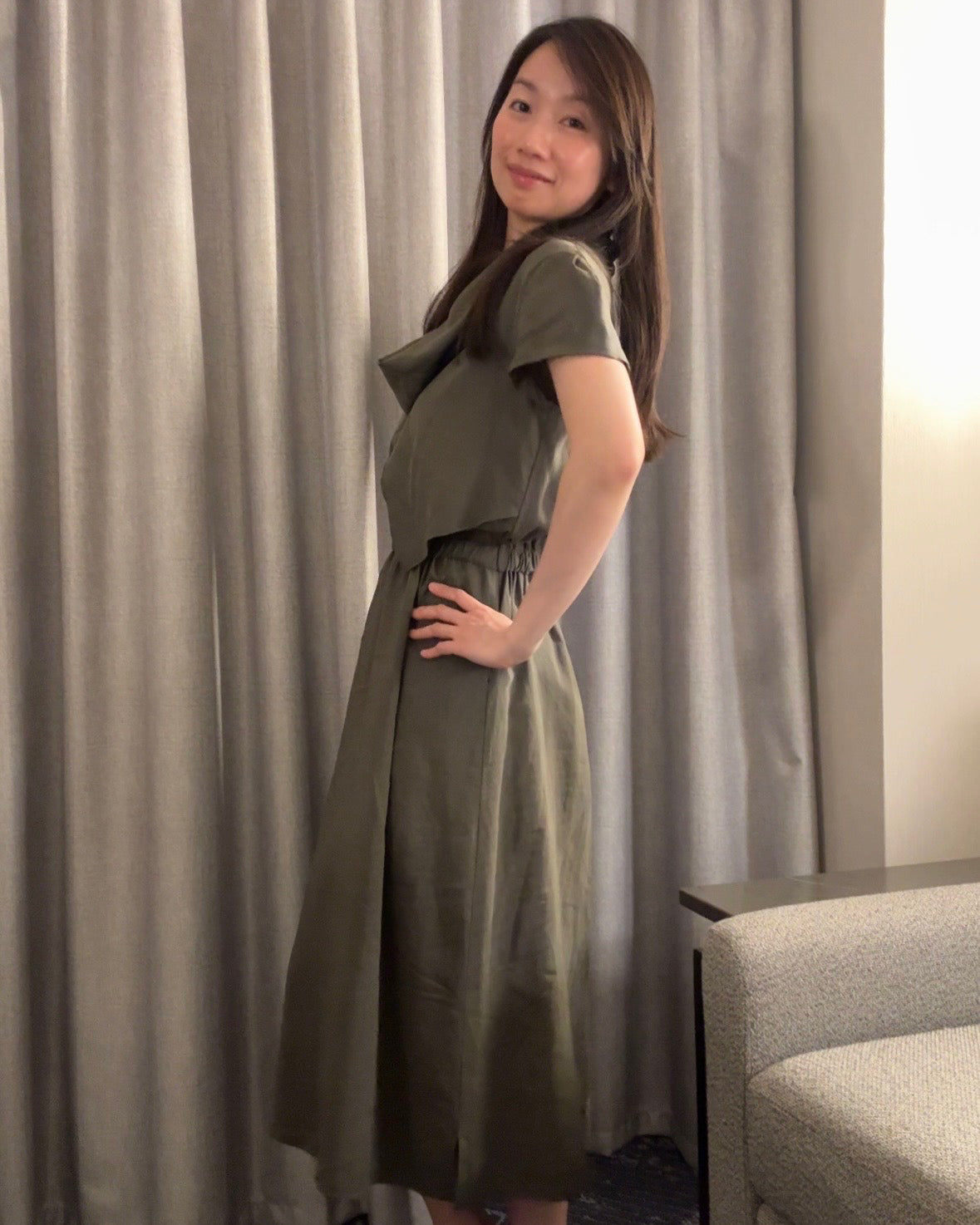 Woman in a green dress standing in front of a curtain
